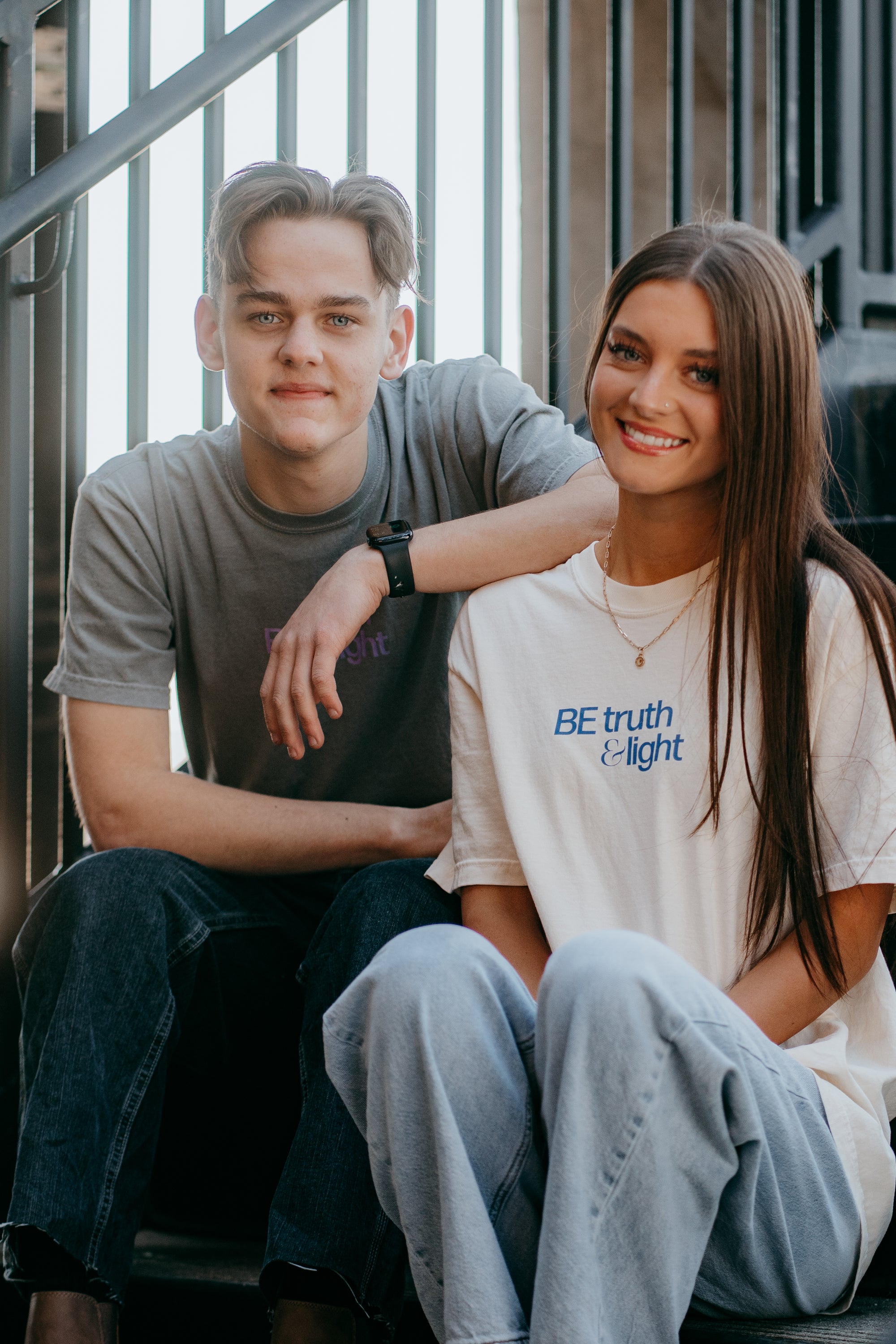 Faith-based "Be Truth &amp; Light" graphic tee styled by female model next to male model wearing Transformed Christian shirt with scripture back print.