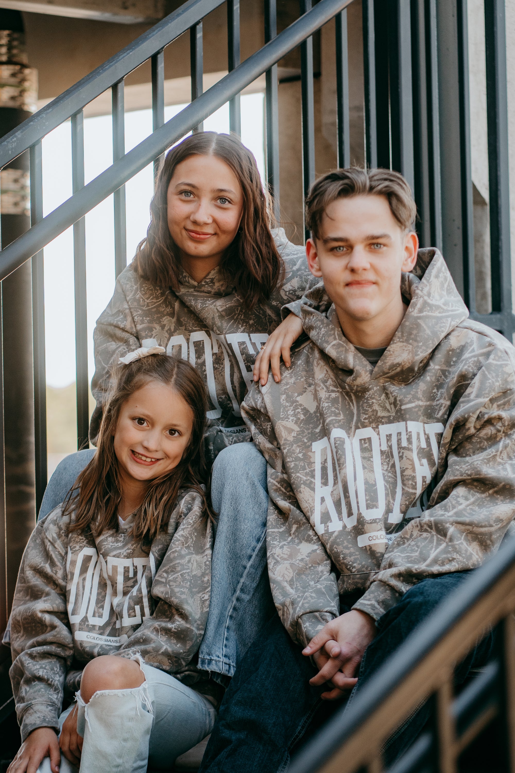 Camo ROOTED hoodie streetwear design with bold lettering and ‘Colossians 3:3’ Scripture detail worn by models.
